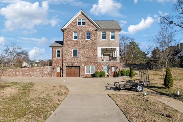 view of front of property with a garage, driveway, brick siding, and a balcony