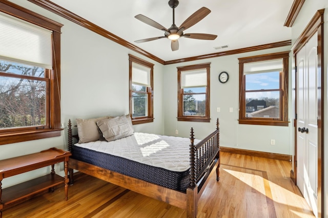 bedroom featuring baseboards, visible vents, ceiling fan, ornamental molding, and light wood-type flooring