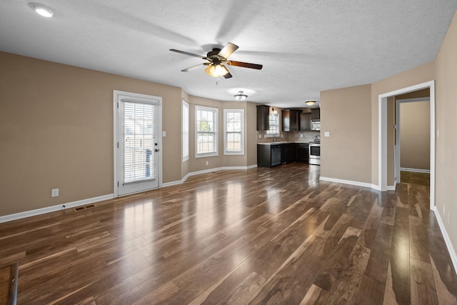 unfurnished living room featuring baseboards, a textured ceiling, a ceiling fan, and dark wood-type flooring