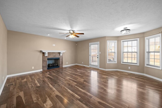 unfurnished living room with a wealth of natural light, visible vents, wood finished floors, and a tile fireplace