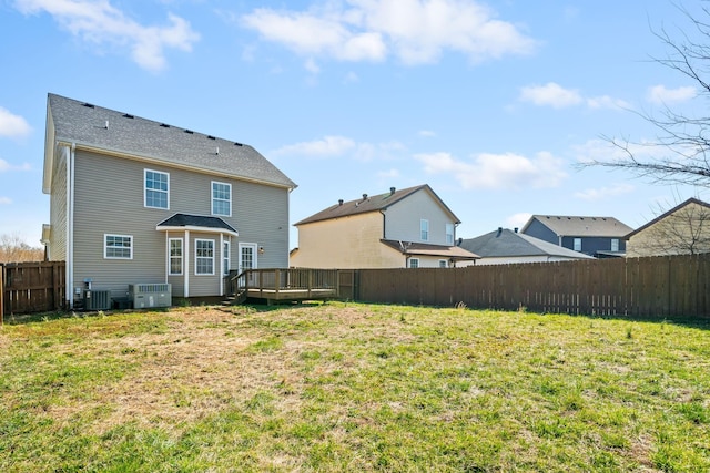 rear view of property with a deck, a yard, a fenced backyard, and central air condition unit