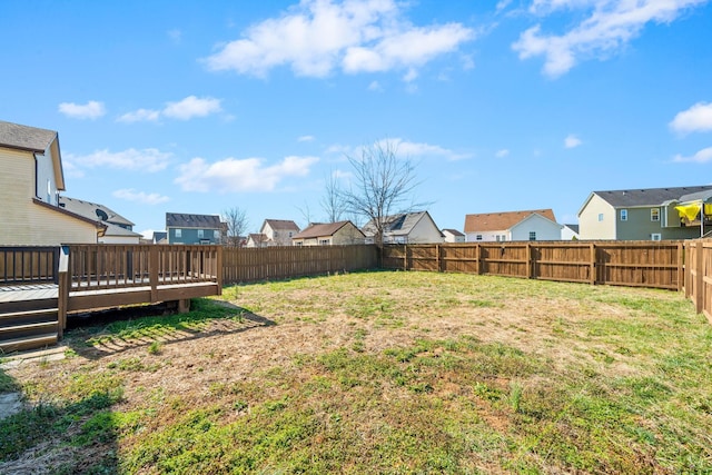 view of yard with a deck, a fenced backyard, and a residential view