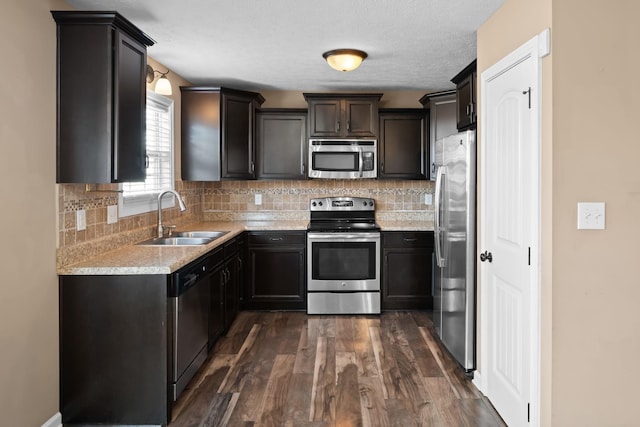 kitchen with backsplash, appliances with stainless steel finishes, dark wood-style flooring, and a sink