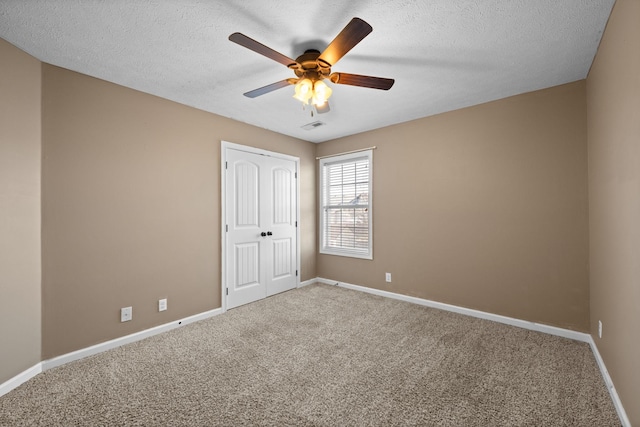 carpeted empty room featuring a ceiling fan, visible vents, a textured ceiling, and baseboards