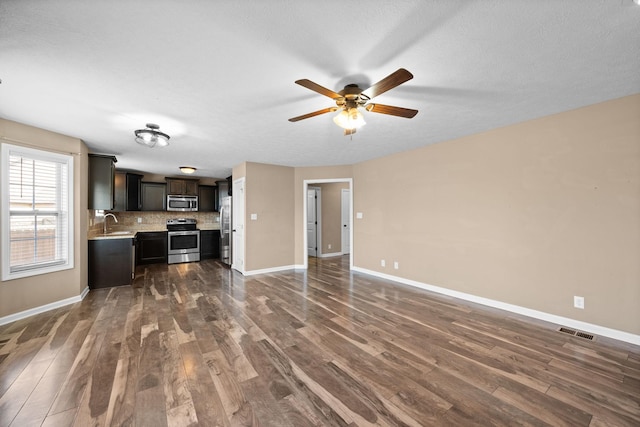 kitchen featuring stainless steel appliances, a sink, visible vents, light countertops, and dark wood finished floors