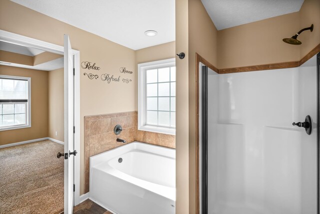 bathroom featuring a shower, a garden tub, and baseboards