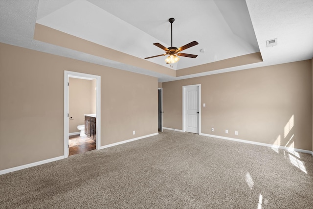 unfurnished bedroom featuring carpet, baseboards, and a raised ceiling