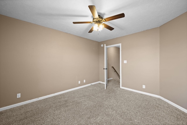 carpeted empty room featuring a ceiling fan, a textured ceiling, and baseboards