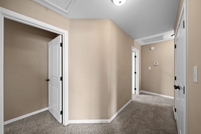 hallway featuring carpet floors, visible vents, a textured ceiling, and baseboards