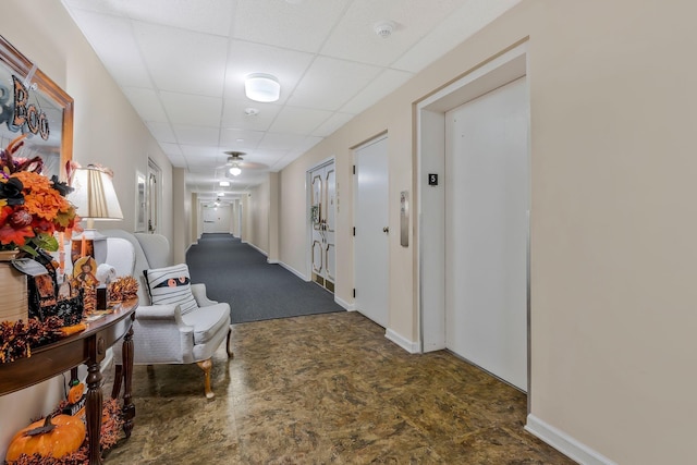 corridor with baseboards, a paneled ceiling, and elevator