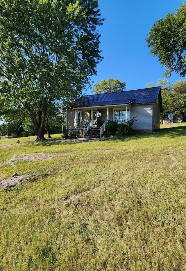 single story home featuring covered porch, metal roof, and a front lawn