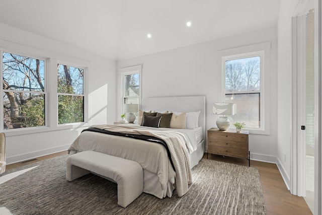 bedroom with baseboards, visible vents, lofted ceiling, wood finished floors, and recessed lighting