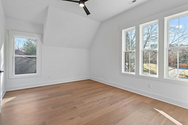 additional living space with baseboards, a healthy amount of sunlight, and light wood finished floors