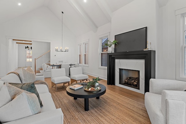 living room featuring stairway, wood finished floors, an inviting chandelier, high vaulted ceiling, and a high end fireplace