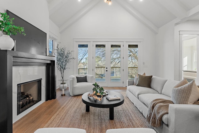 living area featuring high vaulted ceiling, a fireplace, wood finished floors, french doors, and beamed ceiling