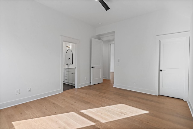 unfurnished bedroom featuring baseboards, ceiling fan, wood finished floors, ensuite bathroom, and a sink