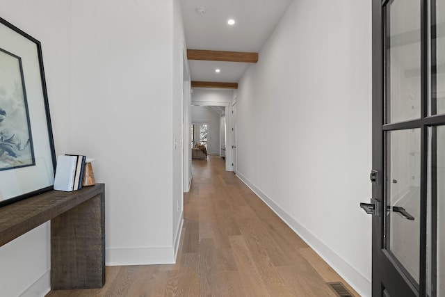 hallway featuring light wood finished floors, baseboards, visible vents, beamed ceiling, and recessed lighting