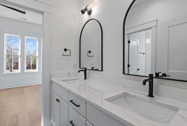 full bath featuring double vanity, visible vents, a sink, and wood finished floors