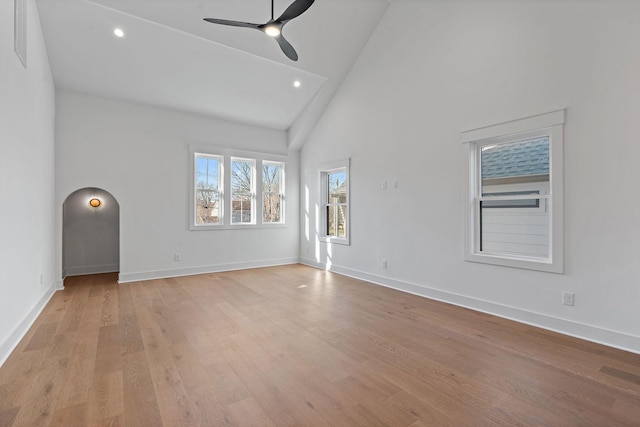 unfurnished living room with arched walkways, ceiling fan, recessed lighting, baseboards, and light wood-style floors