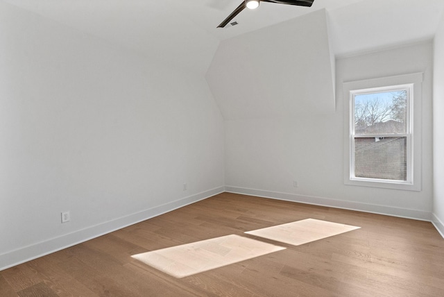 interior space with ceiling fan, vaulted ceiling, baseboards, and wood finished floors