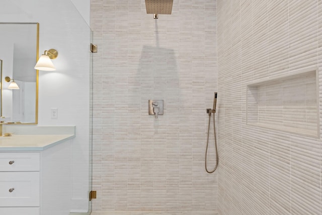 bathroom with a tile shower and vanity