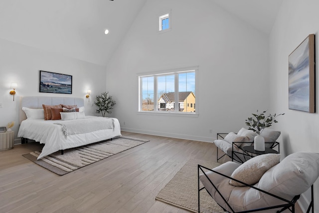 bedroom featuring high vaulted ceiling, baseboards, and light wood finished floors