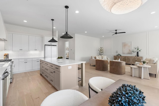 kitchen with dishwasher, a breakfast bar area, open floor plan, light wood-type flooring, and backsplash