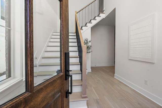 entryway featuring baseboards, stairway, and light wood finished floors