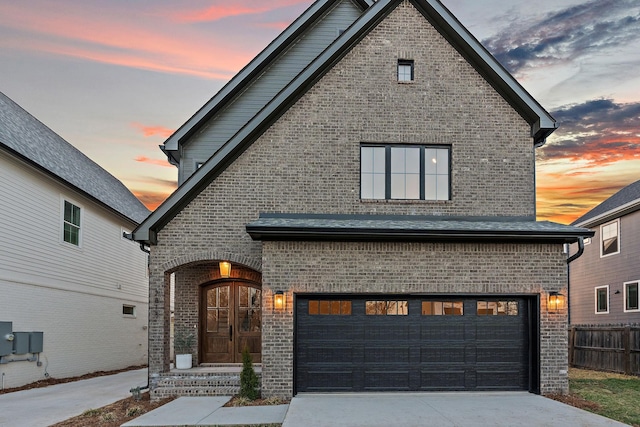 view of front of home featuring a garage, brick siding, driveway, and fence