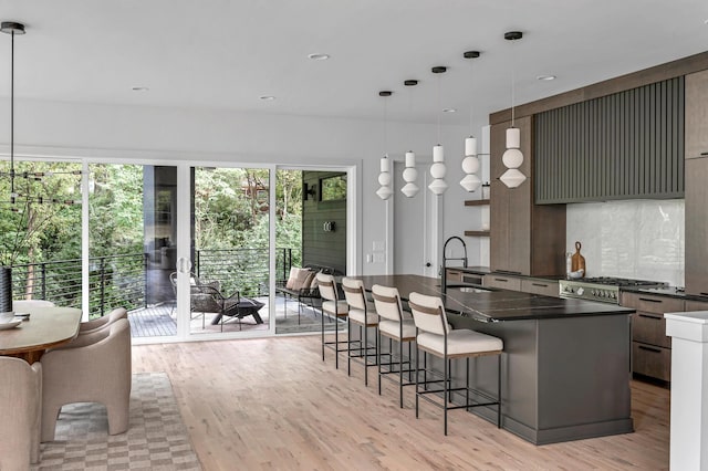 kitchen with dark countertops, a wealth of natural light, a kitchen bar, and a sink