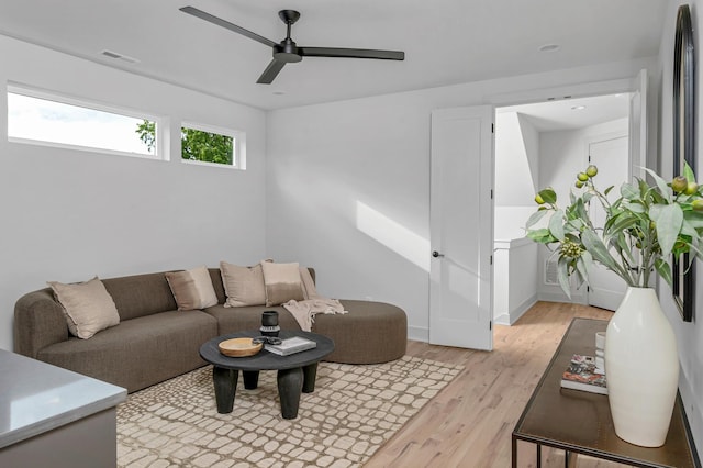 living room featuring ceiling fan, light wood-style flooring, visible vents, and baseboards