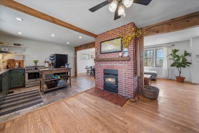 living room with light wood-type flooring, beamed ceiling, a textured ceiling, and a fireplace