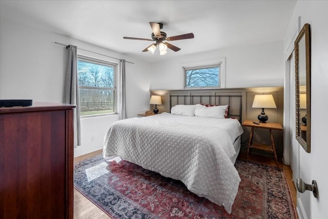 bedroom with multiple windows, wood finished floors, and ceiling fan