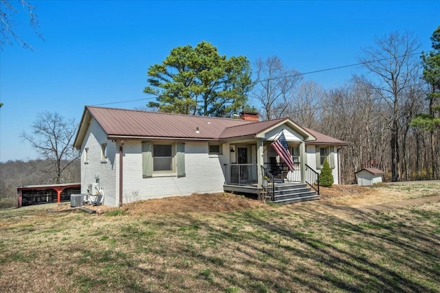 view of front of property with a front yard, covered porch, a chimney, brick siding, and metal roof