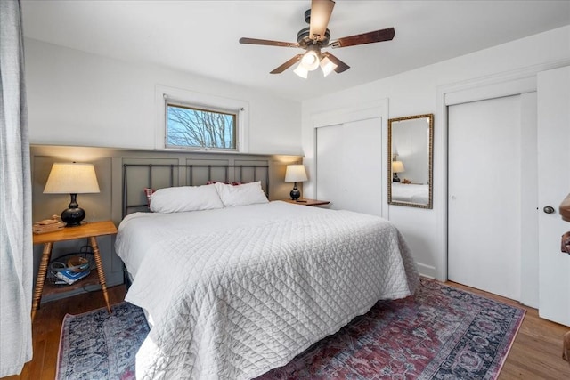 bedroom featuring a ceiling fan, wood finished floors, and multiple closets