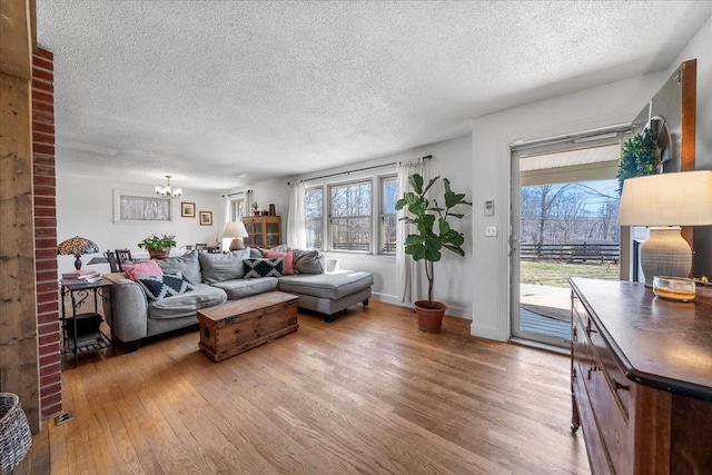 living room with baseboards, a textured ceiling, an inviting chandelier, and hardwood / wood-style flooring