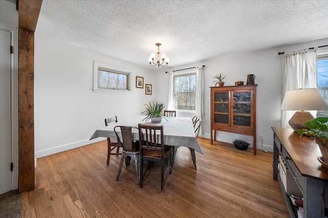 dining area with baseboards, a textured ceiling, an inviting chandelier, and wood finished floors