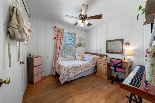 bedroom featuring a decorative wall, ceiling fan, and wood finished floors