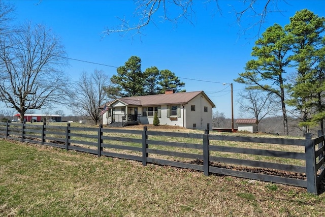 view of front of property with a fenced front yard, a chimney, metal roof, and a front lawn