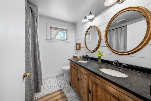 bathroom with double vanity, toilet, baseboards, and a sink