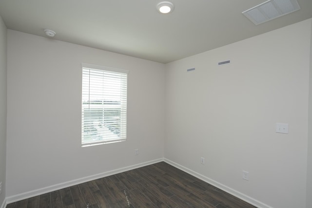 spare room featuring visible vents, dark wood finished floors, and baseboards