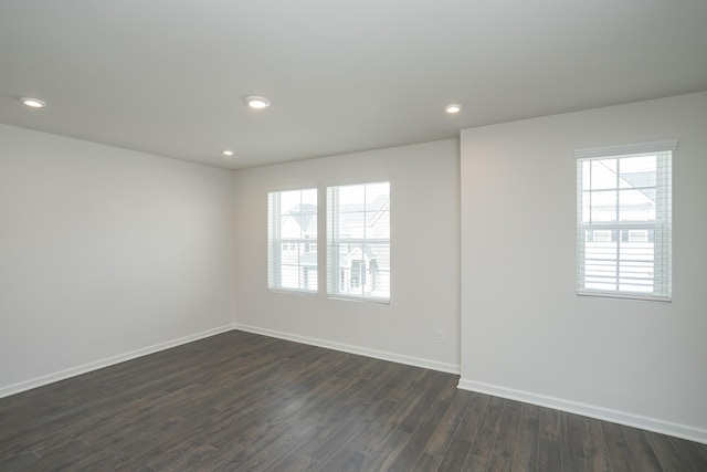 unfurnished room with plenty of natural light, dark wood finished floors, and baseboards