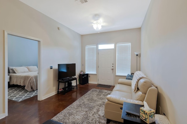 living area with finished concrete flooring, visible vents, and baseboards