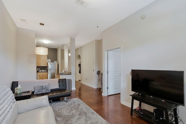 living room with arched walkways, visible vents, and baseboards