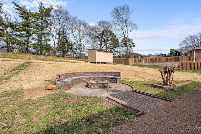 view of yard featuring a shed, fence, a fire pit, and an outbuilding