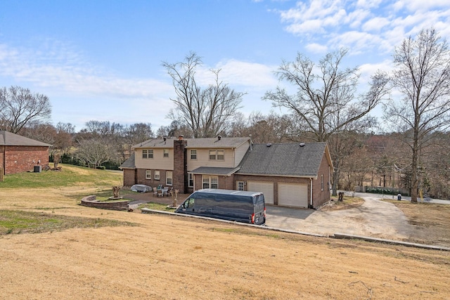 view of front of house with brick siding, a chimney, a garage, driveway, and a front lawn