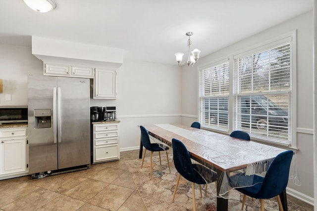 dining space with light tile patterned floors, baseboards, and a notable chandelier