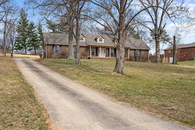 cape cod home with brick siding, roof with shingles, a porch, a front yard, and fence