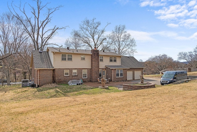 back of house featuring a chimney, a lawn, an attached garage, central AC, and driveway