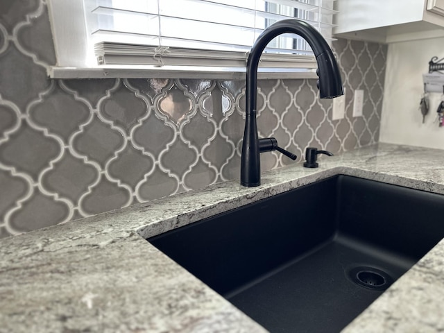 interior details with a sink and light stone countertops